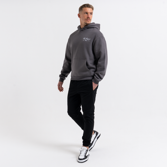 Man wearing a grey hoodie and blackcargo pants on a white background