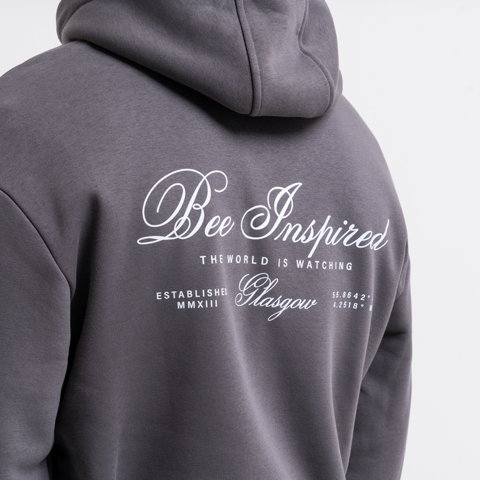Grey hoodie with 'Bee Inspired' text on the back against a light gray background