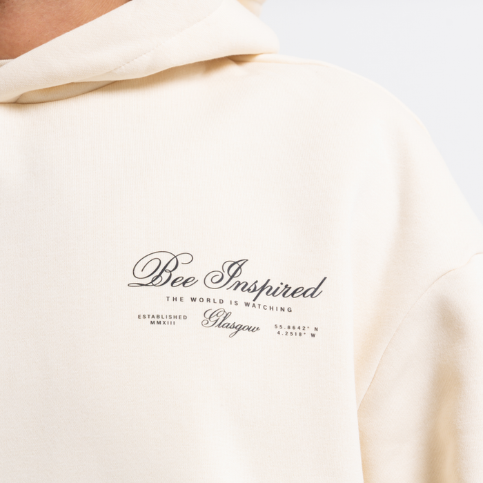 Sand hoodie with 'Bee Inspired' text on a white background
