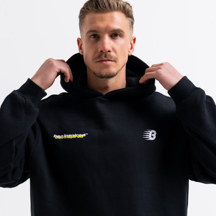 Man wearing a black hoodie with logos on a plain background