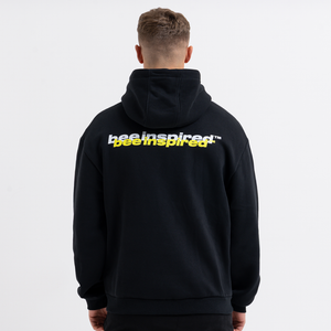 Person wearing a black hoodie with 'Bee Inspired' text on the back against a white background