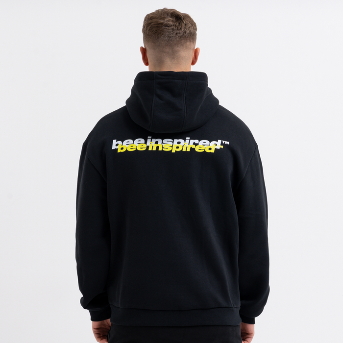 Person wearing a black hoodie with 'Bee Inspired' text on the back against a white background