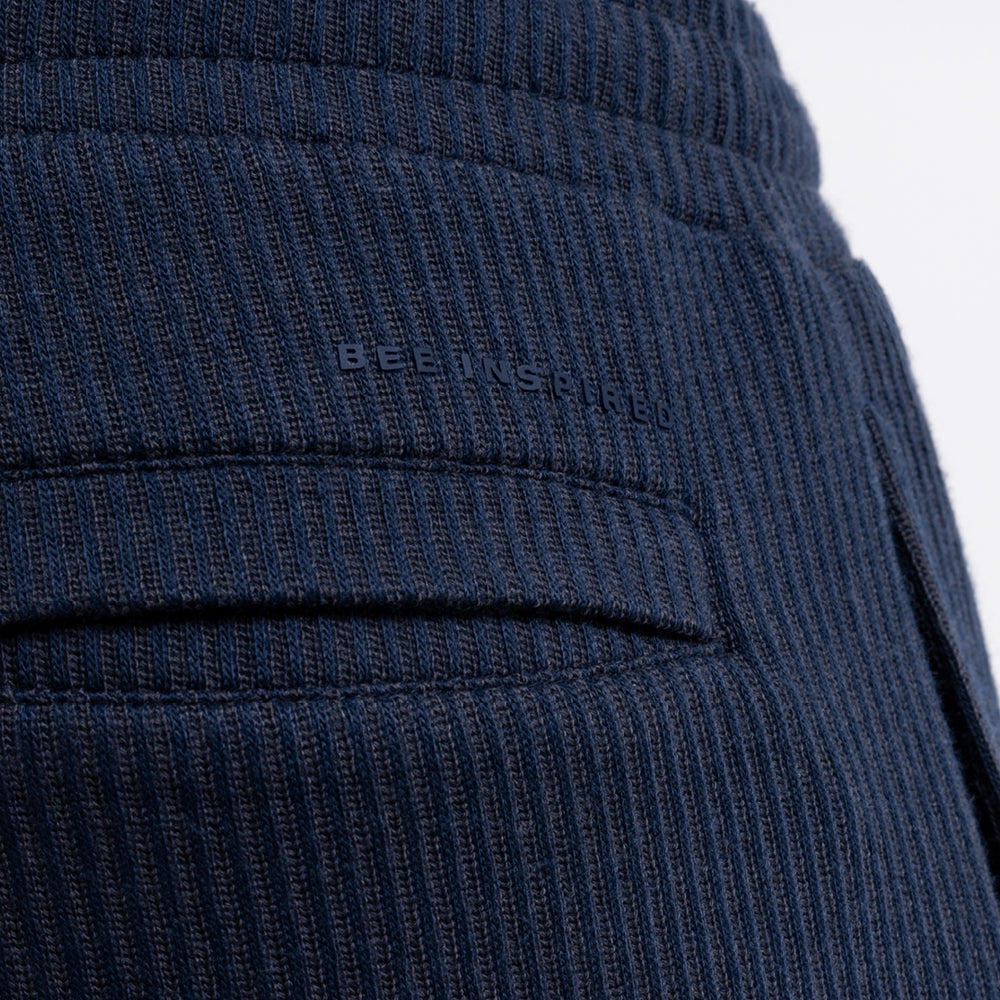 Close up of a linear logo above the back pocket on the Ake Short in dark navy