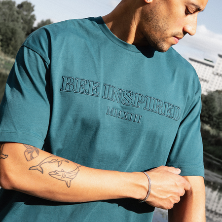 Bee Inspired Levit T-Shirt in Teal, tee with embroidered branding across the chest, close-up crop shot