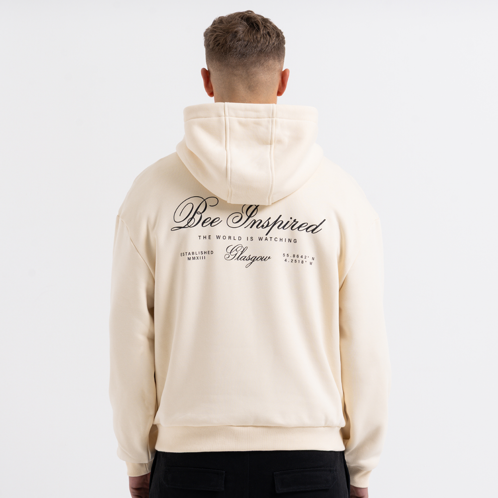 Man wearing a sand hoodie with text on the back against a white background