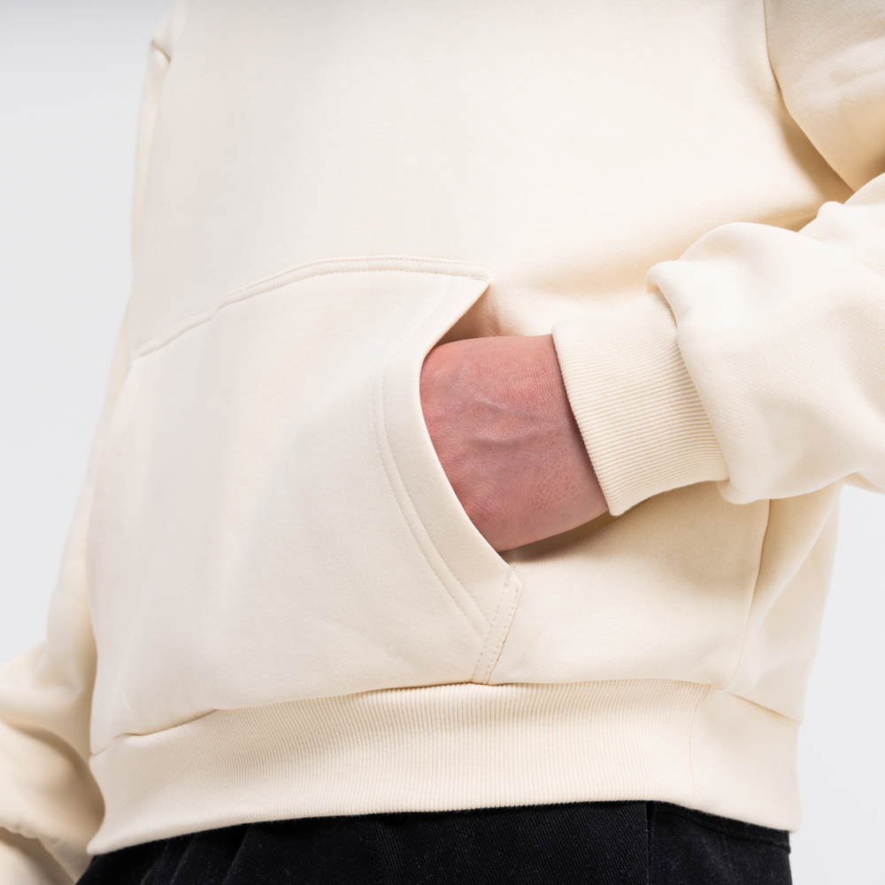 Close-up of a person wearing a sand coloured hoodie with hand in pocket