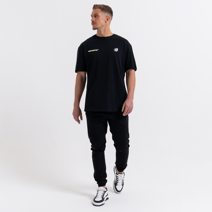 Man wearing a black t-shirt and cargo pants with a logo on a white background